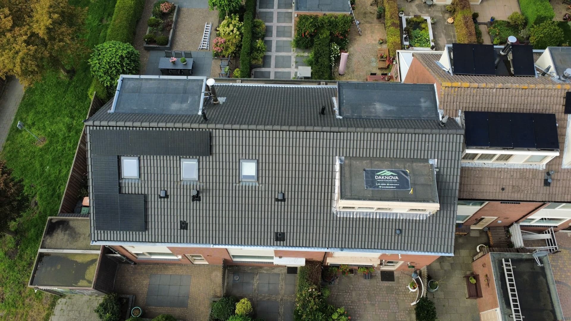 Het nieuwe donkere pannendak recht van bovenaf gezien, met dakramen en zonnepanelen