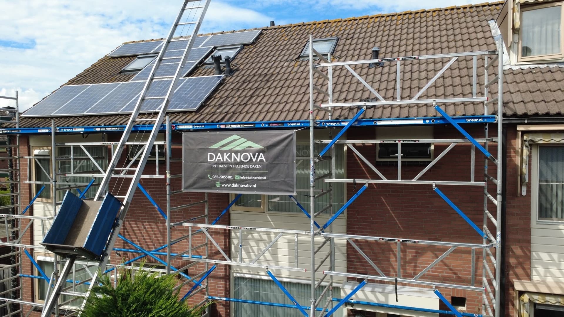 Steiger met ladderlift en het Daknova-spandoek tegen de gevel tijdens de dakrenovatie